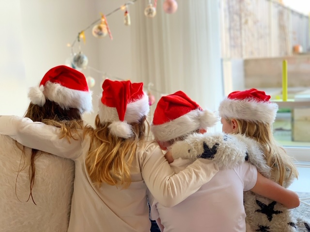 4 kids voor de kerstboom met kerstmutsen kerstkaart